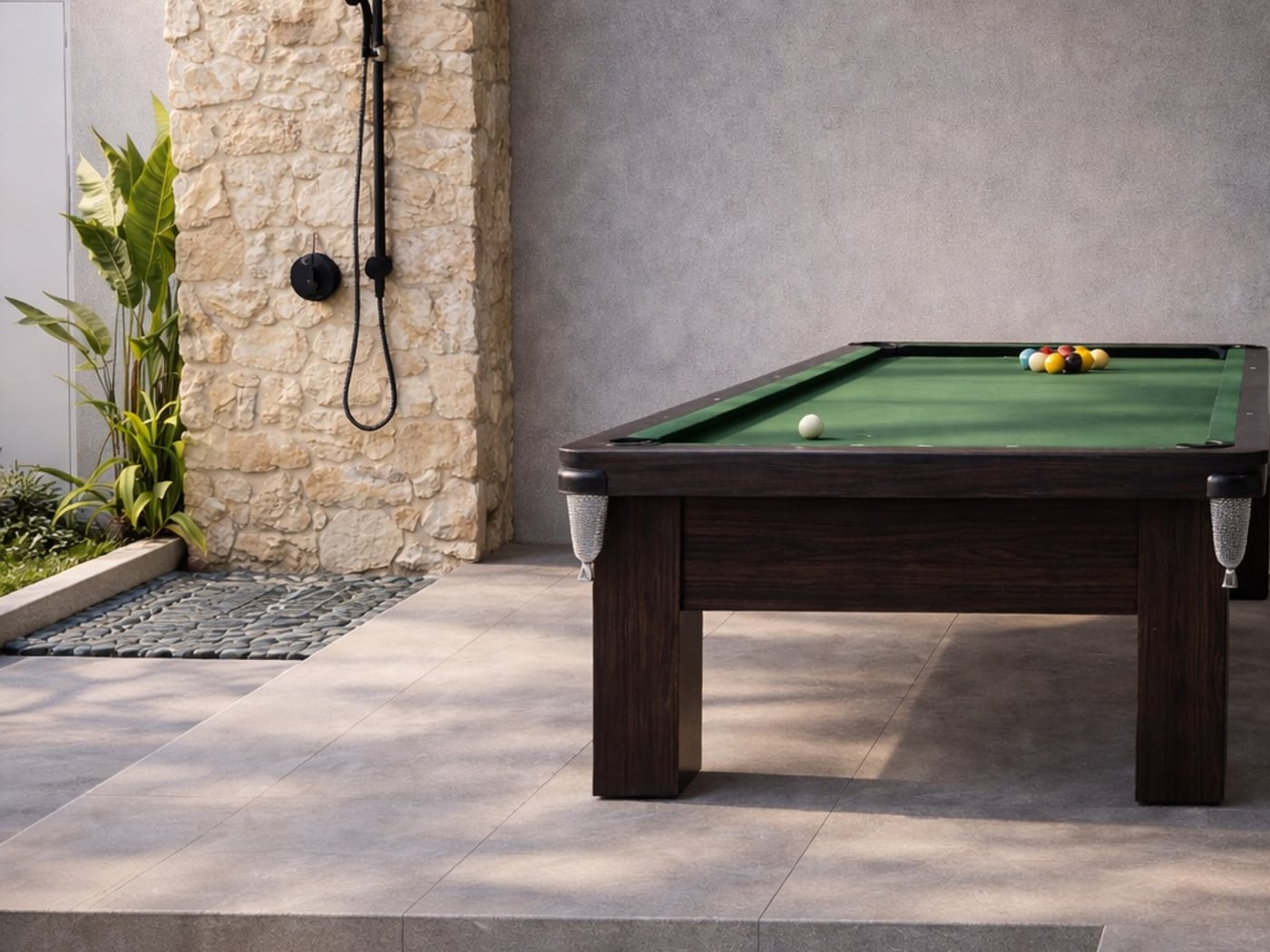 Área de lazer externa com mesa de sinuca verde e ducha de pedra